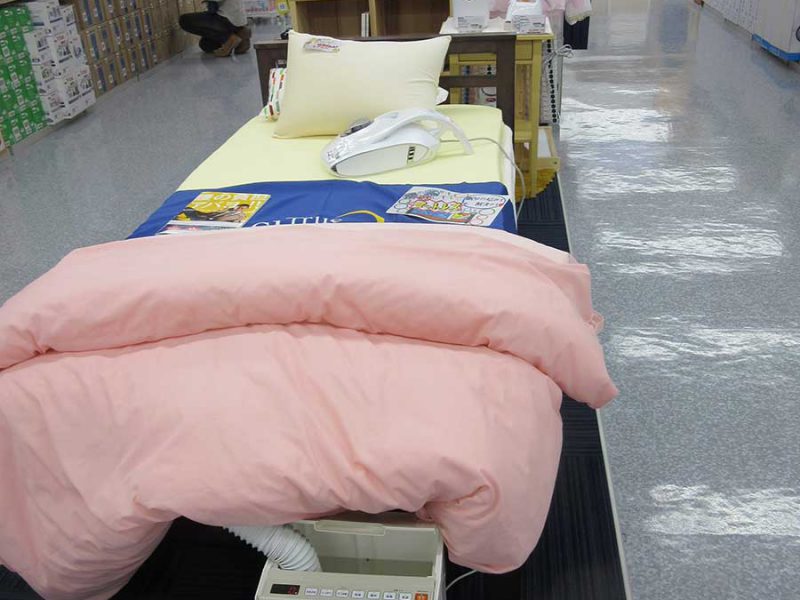ベッドを置き、手前にふとん乾燥機、敷き布団の上のふとんクリーナー、奥のサイドスタンドには加湿器類を配置して快適な眠りを提案